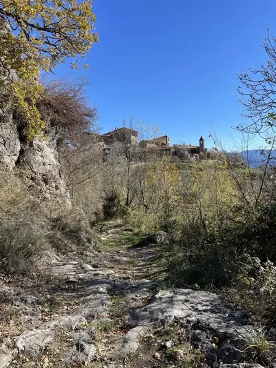 Sender pedregós entre Antist i Estavill, amb cases de pedra i un campanar al fons.
